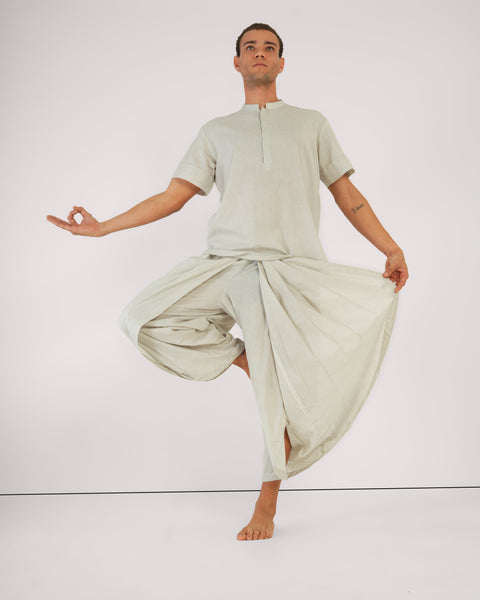 Male performing tree pose yoga asana in Vibhuti Grey linen cotton yoga set, front-view, breathable natural fabric, white studio background.