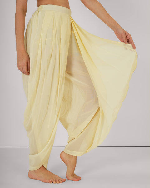 Close-up of Jasmine Veil YogaFlow pants in sheer cotton — pleated drape lifted gently, revealing airy, sunlit movement.