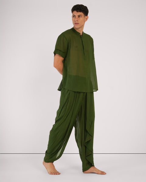 Male standing in relaxed pose, side view, in Mehndi green 100% cotton yoga set, natural breathable fabric, white studio background.